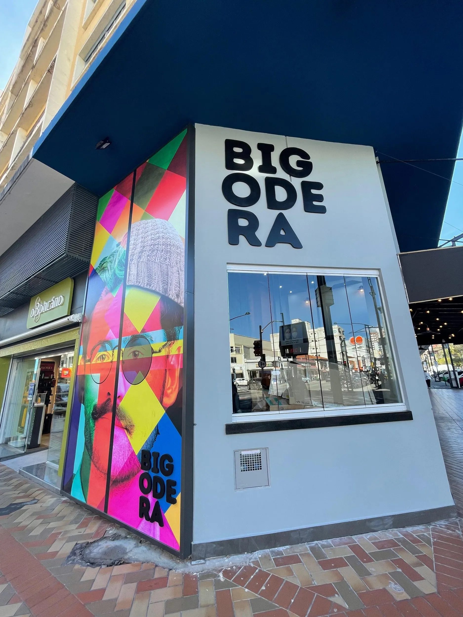 Fachada de esquina da Bigodera, com mural pop-art colorido e o letreiro em três linhas