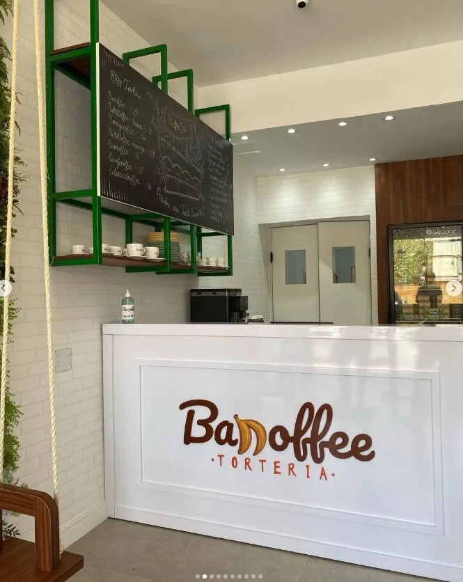 Foto da obra entregue: balcão branco com a marca e estantes verdes com lousa de menu