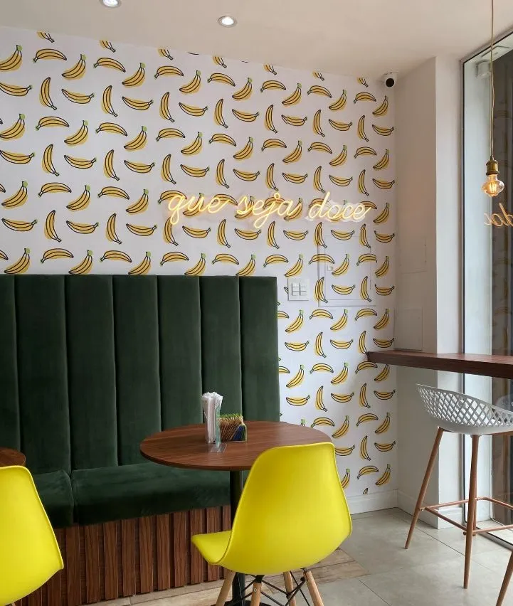 Foto da obra entregue: parede de bananas com neon "que seja doce" e banco verde