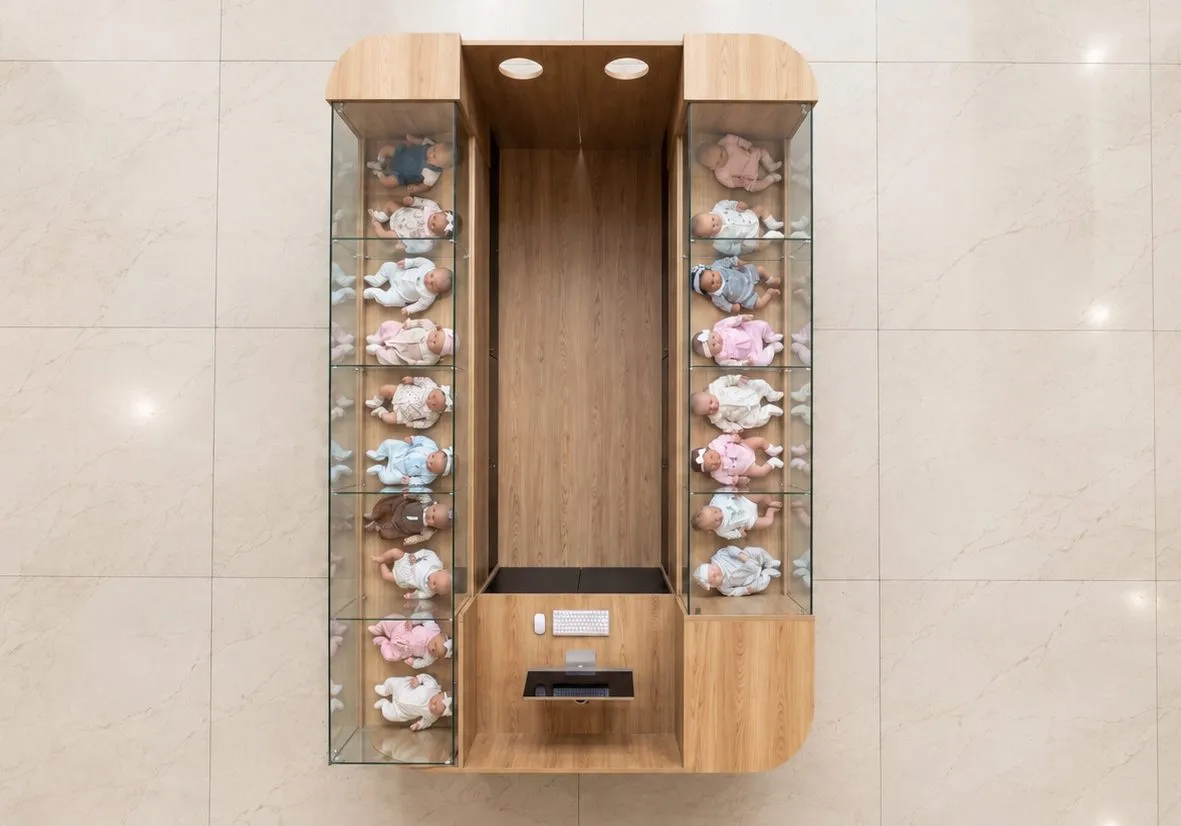 Vitrine vertical iluminada com as bonecas expostas em nichos
